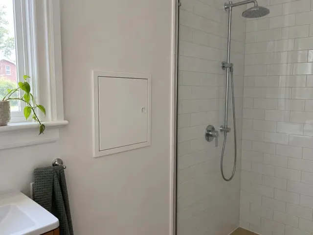 Neat access panel on a bathroom wall beside a tiled shower and window in Leichhardt
